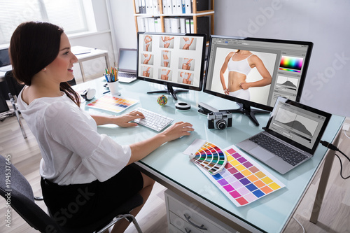 Female Designer Working With Photographs On Multiple Computer