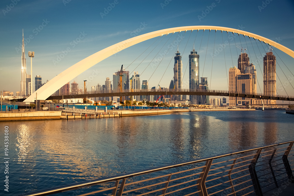 Fototapeta premium Dubaj, Zjednoczone Emiraty Arabskie - luty 2018: Kolorowy zachód słońca nad drapaczami chmur w centrum Dubaju i nowo wybudowanym mostem tolerancji, patrząc z kanału wodnego w Dubaju.