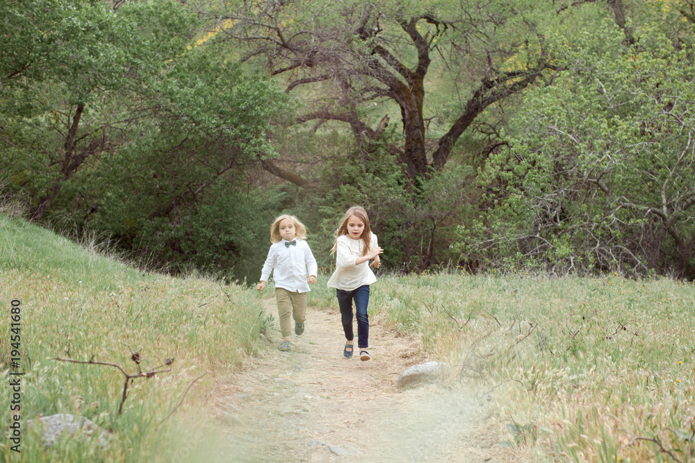 Cute siblings running on path in a field during spring Cute siblings running on path in a field during spring