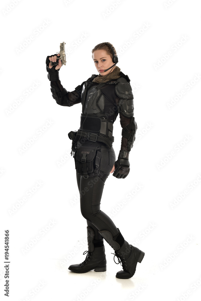 full length portrait of female  soldier wearing black  tactical armour, holding a gun, isolated on white studio background.