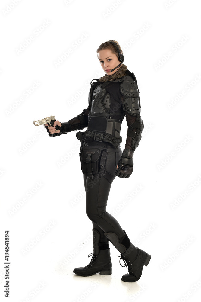 full length portrait of female soldier wearing black tactical armour, holding a gun, isolated on white studio background. full length portrait of female soldier wearing black tactical armour, holding a gun, isolated on white studio background.