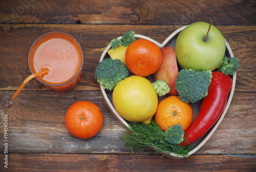 Fruits and Vegetables in Heart shaped Wooden Box. Broccoli, apples, Pepper, tangerine and glass of juice over Wooden Background. Banner. Health food Concept with copy space.