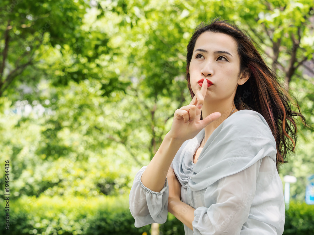 Beautiful young brunette Asian woman making silent gesture with index finger on lips. Outdoor fashion portrait of glamour young Chinese stylish lady. Emotions, people, beauty and lifestyle concept. Beautiful young brunette Asian woman making silent gesture with index finger on lips. Outdoor fashion portrait of glamour young Chinese stylish lady. Emotions, people, beauty and lifestyle concept.