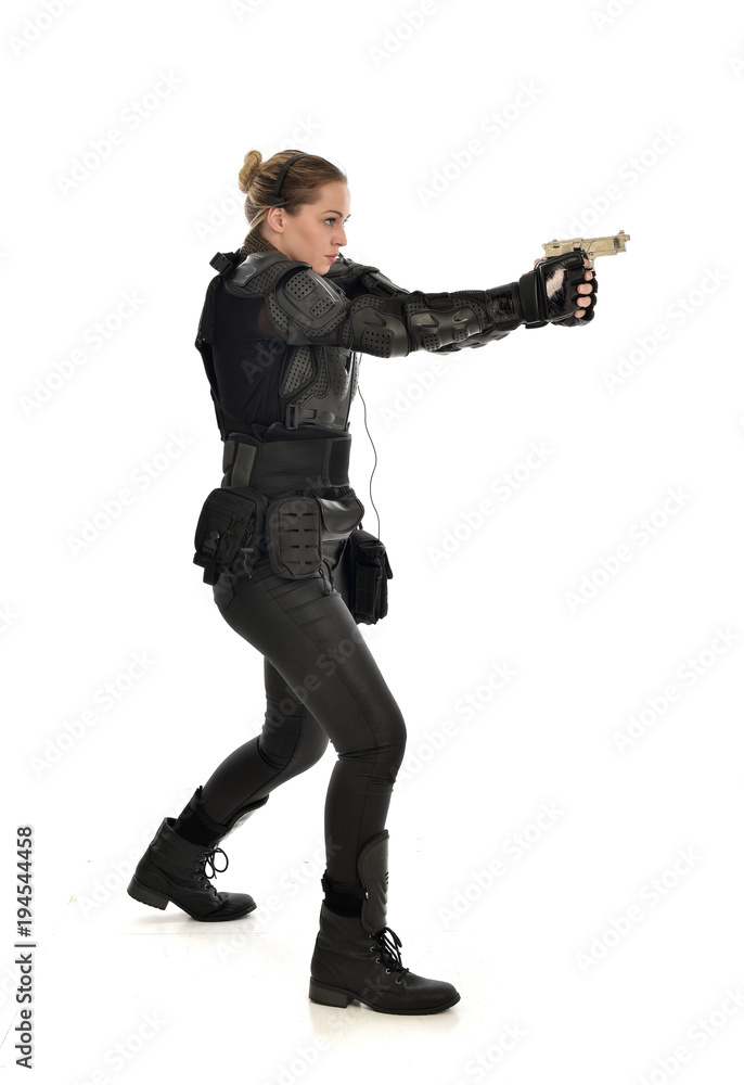 full length portrait of female soldier wearing black tactical armour, holding a gun, isolated on white studio background. full length portrait of female soldier wearing black tactical armour, holding a gun, isolated on white studio background.