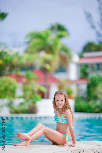 Adorable little girl have fun near swimming pool outdoors