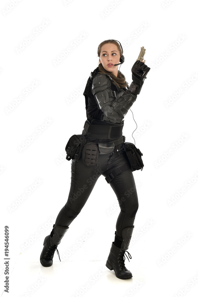 full length portrait of female  soldier wearing black  tactical armour, holding a gun, isolated on white studio background.