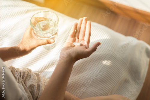 Fotografia Woman holding pills or capsules on hand and a glass of water