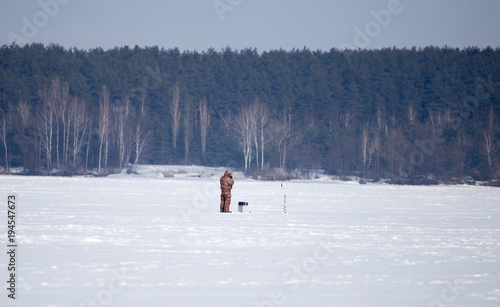 A man catches fish on ice in winter