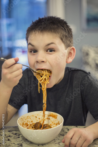 Hungry and Excited boy taking a huge bite of spaghetti