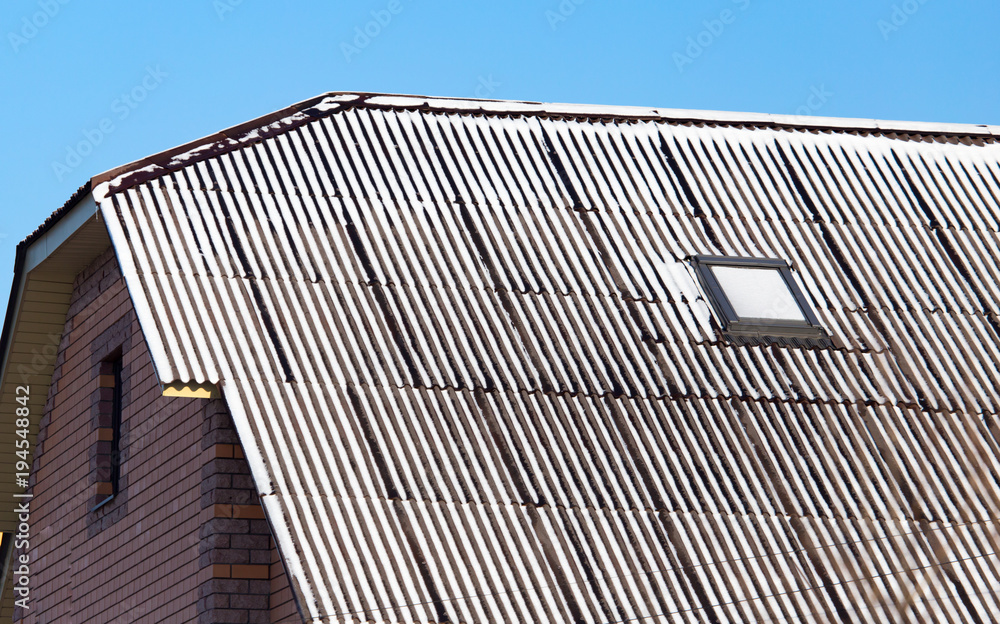 Snow on the roof of the house in winter