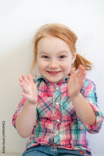 The girl claps her hands on the white background