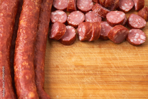 Thin smoked sausage whole and sliced on a wooden background. Close-up.