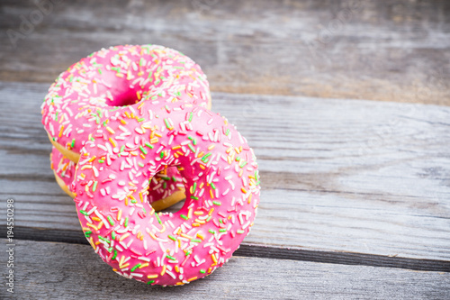 Donut with sprinkles on the rustic wooden background. Selective focus.