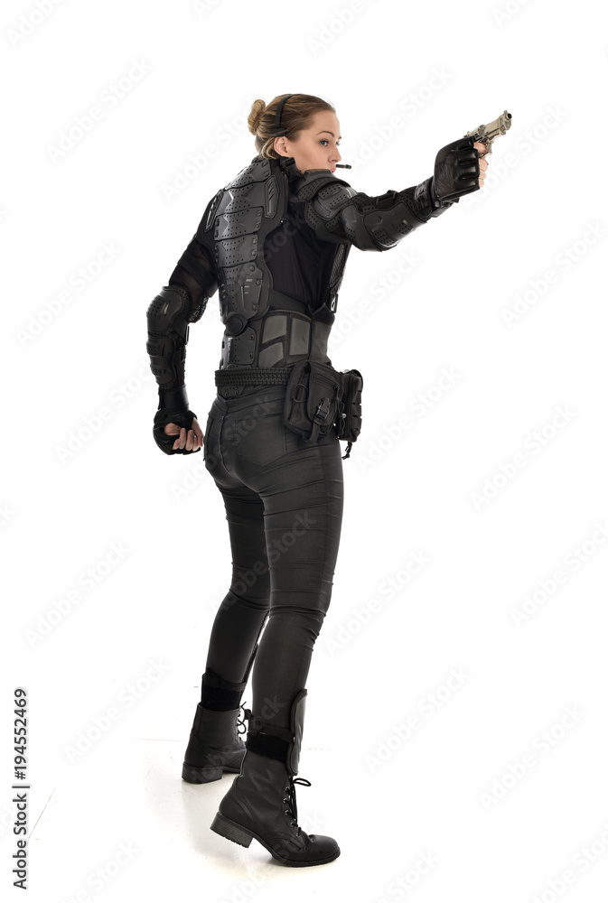 full length portrait of female  soldier wearing black  tactical armour, holding a gun, isolated on white studio background.