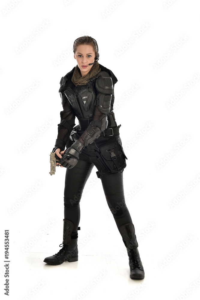 full length portrait of female  soldier wearing black  tactical armour, holding a gun, isolated on white studio background.