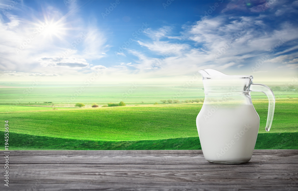 Jug of fresh milk against background of wavy pasture Jug of fresh milk against background of wavy pasture