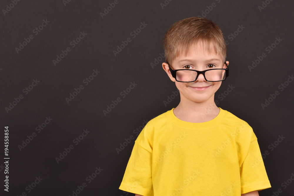 A boy in glasses. A shot of a young man in the studio. A child in a yellow T-shirt.