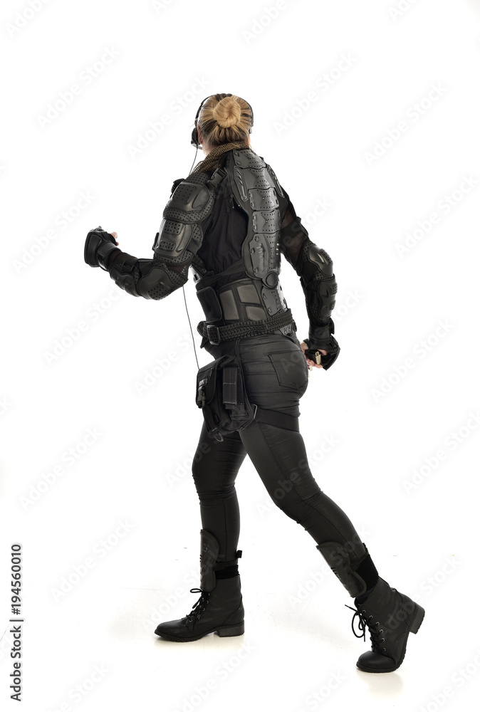 full length portrait of female soldier wearing black tactical armour, holding a gun, isolated on white studio background. full length portrait of female soldier wearing black tactical armour, holding a gun, isolated on white studio background.