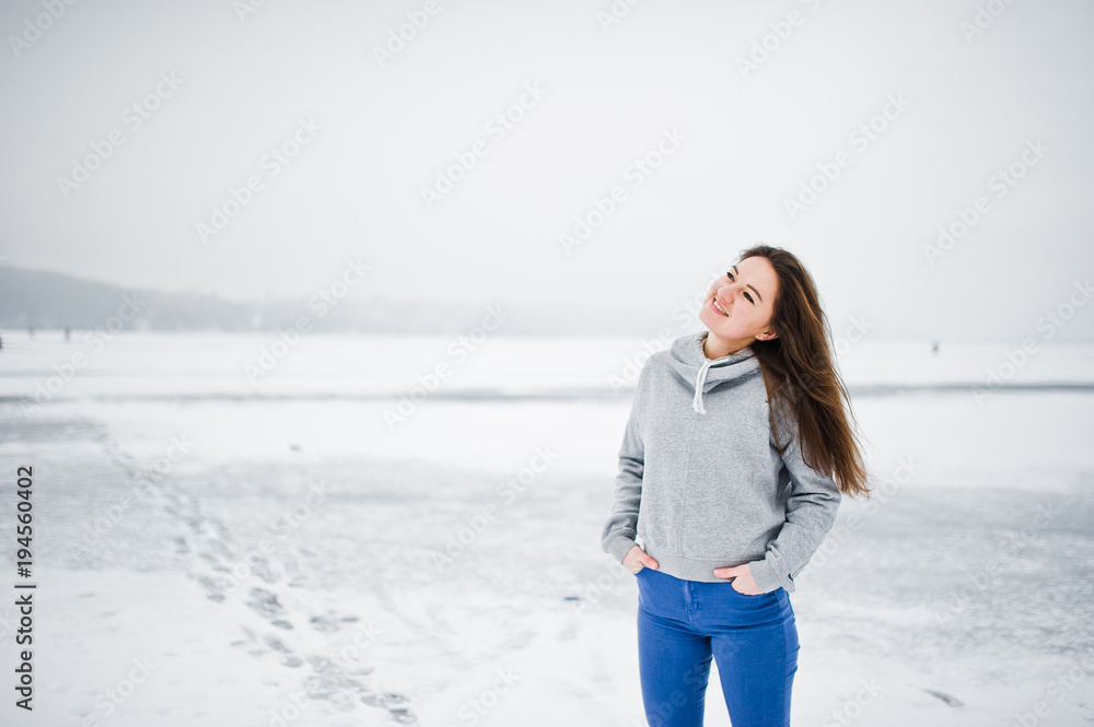 Funny girl wear on hoody sweater and jeans, at frozen lake in winter day. Funny girl wear on hoody sweater and jeans, at frozen lake in winter day.
