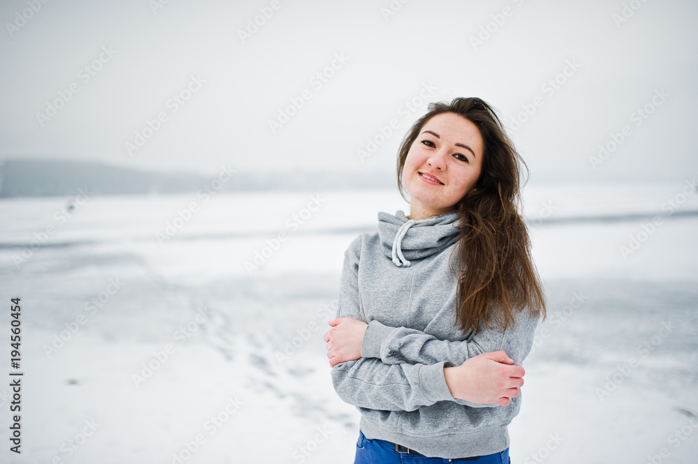 Funny girl wear on hoody sweater and jeans, at frozen lake in winter day. Funny girl wear on hoody sweater and jeans, at frozen lake in winter day.