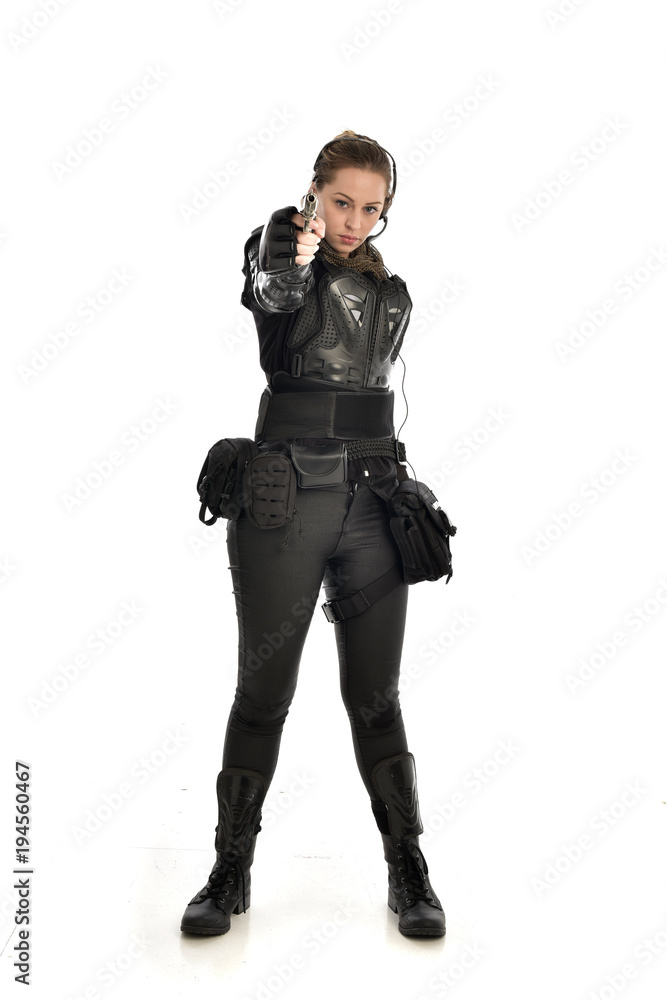 full length portrait of female soldier wearing black tactical armour, holding a gun, isolated on white studio background. full length portrait of female soldier wearing black tactical armour, holding a gun, isolated on white studio background.