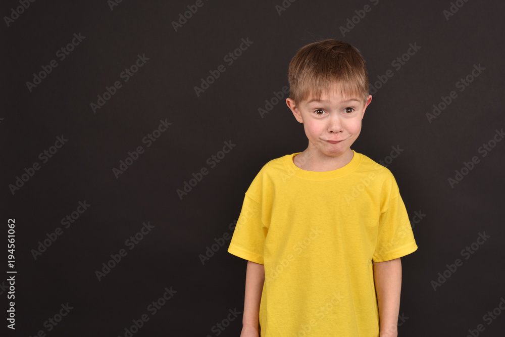 A boy on a dark background. Shooting a child in the studio. A young man in a yellow T-shirt. A boy on a dark background. Shooting a child in the studio. A young man in a yellow T-shirt.