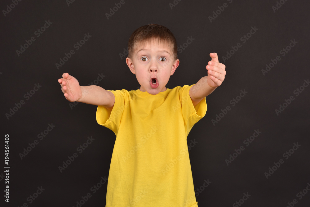 A boy on a dark background. Shooting a child in the studio. A young man in a yellow T-shirt. A boy on a dark background. Shooting a child in the studio. A young man in a yellow T-shirt.