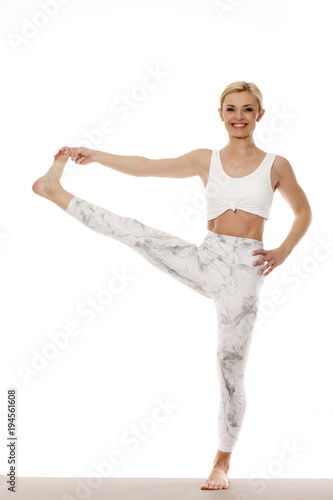 Yoga, sport, training and lifestyle concept - Young blonde woman doing yoga exercise. Portrait of young beautiful woman in white sportswear doing yoga practice. Standing pose.
