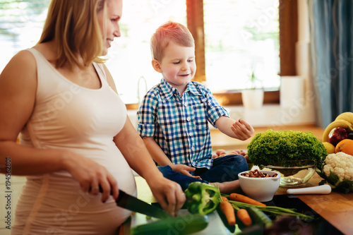 Pregnant woman preparing meal with son