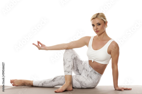 Yoga, sport, training and lifestyle concept - Young blonde woman relaxes while exercising yoga Portrait of young beautiful woman in white sportswear in relax pose.
