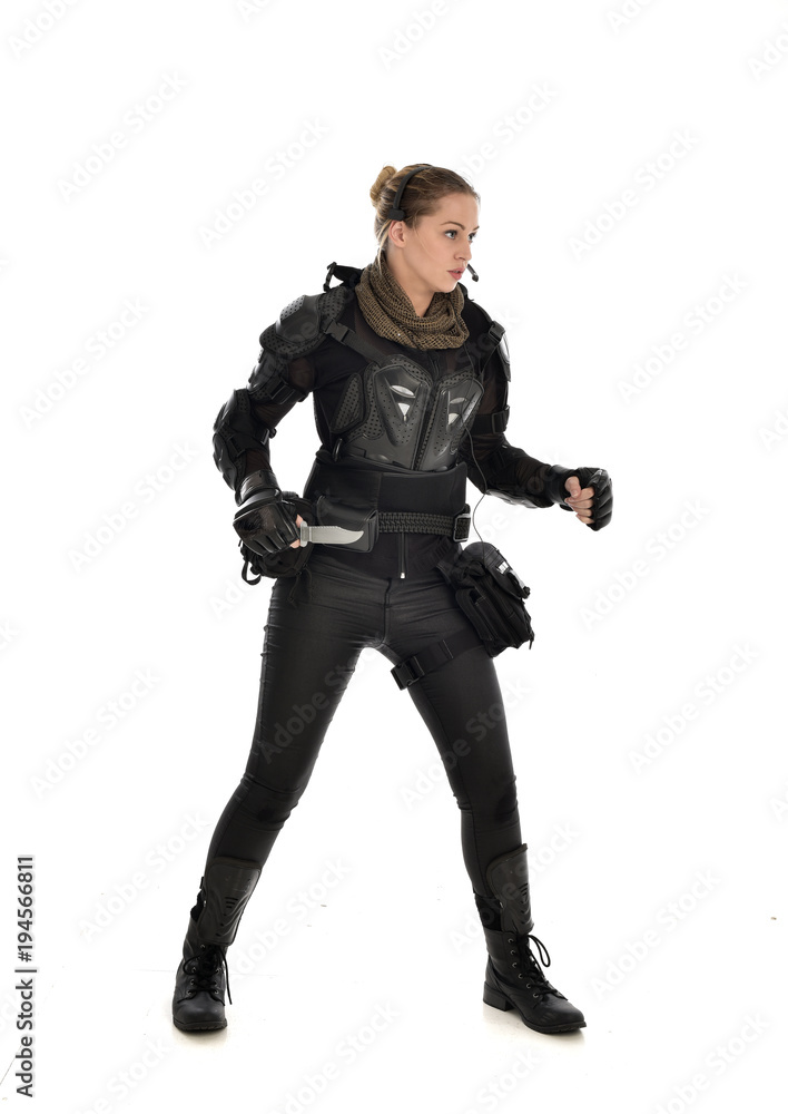 full length portrait of female soldier wearing black tactical armour, holding a remote knife, isolated on white studio background. full length portrait of female soldier wearing black tactical armour, holding a remote knife, isolated on white studio background.