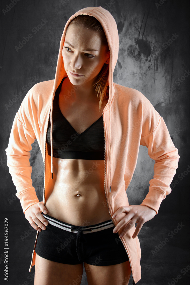 Frau in Sportbekleidung und Hoodie ist fit, muskulös und sportlich Frau in Sportbekleidung und Hoodie ist fit, muskulös und sportlich