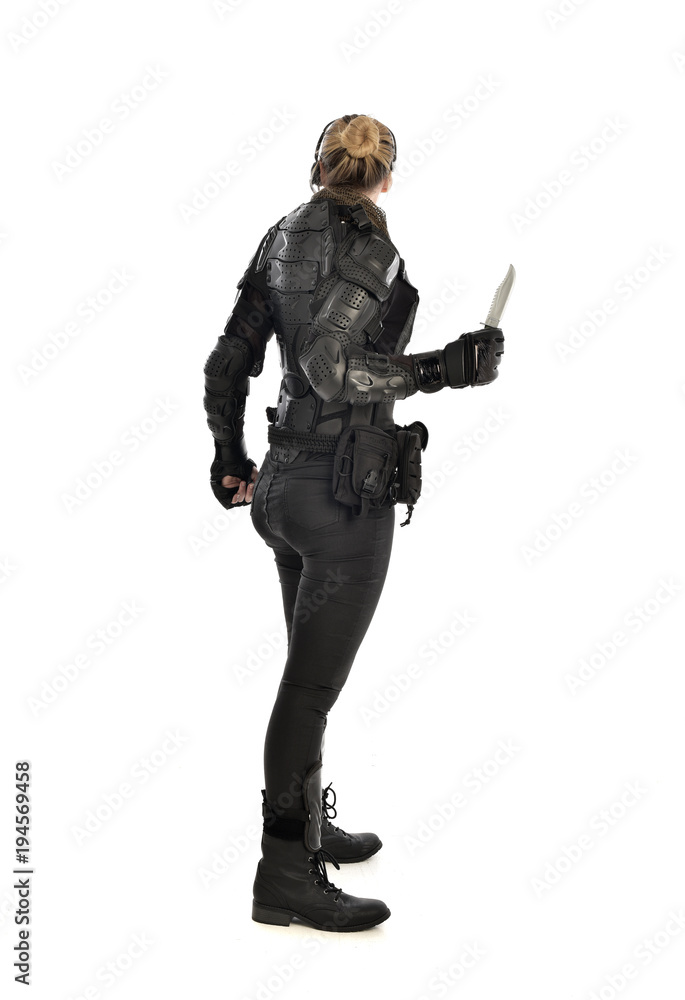 full length portrait of female  soldier wearing black  tactical armour, holding a remote knife, isolated on white studio background.