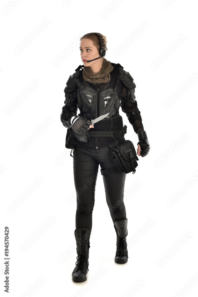full length portrait of female soldier wearing black tactical armour, holding a remote knife, isolated on white studio background. full length portrait of female soldier wearing black tactical armour, holding a remote knife, isolated on white studio background.