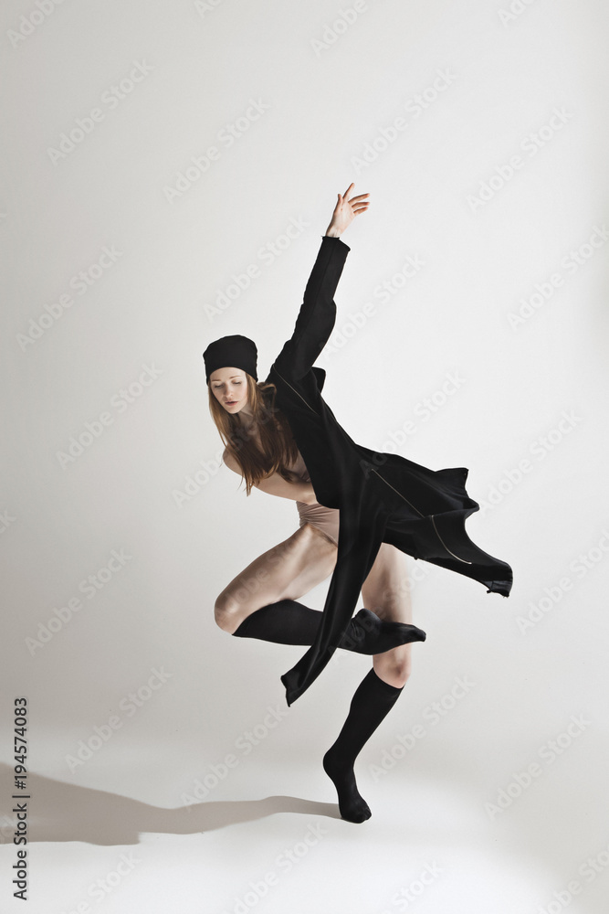 Obraz premium Young beautiful dancer in beige swimsuit dancing on gray background