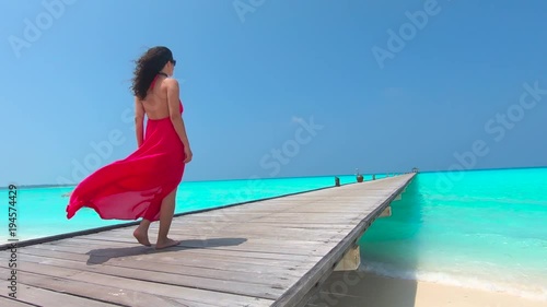 Woman in Red Dress  Walking on the Tropical Pier Dock Landscape with Blue Water in Slow Motion