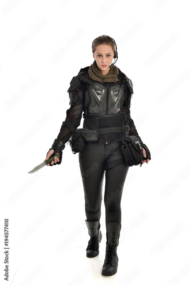 full length portrait of female soldier wearing black tactical armour, holding a remote knife, isolated on white studio background. full length portrait of female soldier wearing black tactical armour, holding a remote knife, isolated on white studio background.