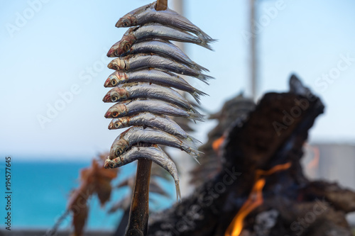 an Holzkohle gegrillte Sardinen mit Flammen und glühender Kohle imHintergrund