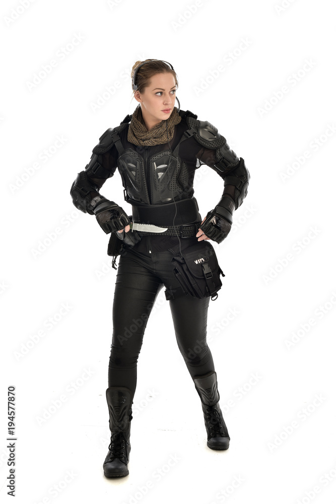 full length portrait of female soldier wearing black tactical armour, holding a remote knife, isolated on white studio background. full length portrait of female soldier wearing black tactical armour, holding a remote knife, isolated on white studio background.