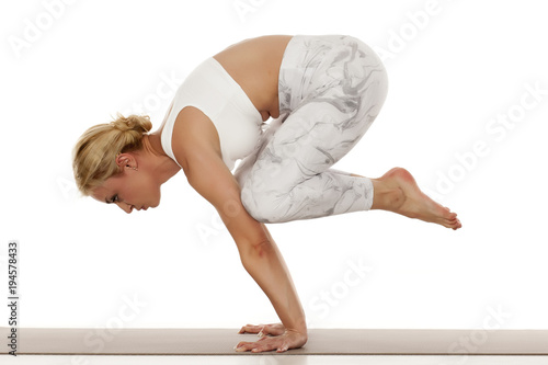 Yoga, sport, training and lifestyle concept - Young blonde woman in white sportswear doing yoga practice.Crane pose ,bakasana