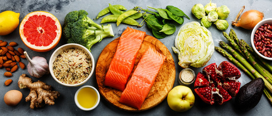 Healthy food clean eating selection: fish, fruit, vegetable, cereal, leaf vegetable on gray concrete background copy space