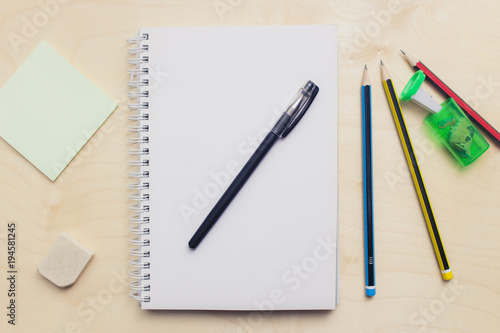 Open blank notebook on wood background with pencil.