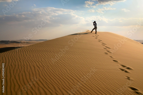 Photographer in sand dunes of Grand Sand Sea during desert safari in Egypt close to oasis Wahat Siwa
