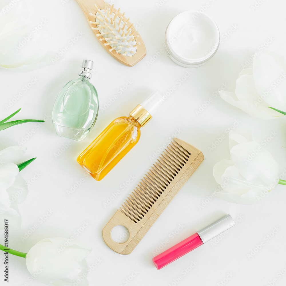 Female cosmetics, perfume, combs and tulips flowers on white background. Beauty blogger composition. Flat lay, top view Female cosmetics, perfume, combs and tulips flowers on white background. Beauty blogger composition. Flat lay, top view