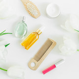 Female cosmetics, perfume, combs and tulips flowers on white background. Beauty blogger composition. Flat lay, top view