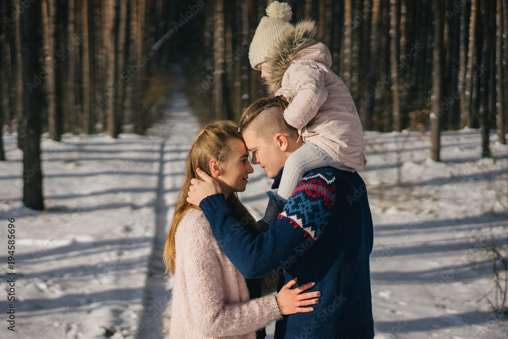 Fototapeta premium side view of beautiful happy young family spending time together in winter forest