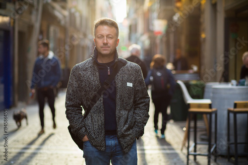 Handsome middle-aged man walking autumn street. Urban male portrait, image toned and noise added. photo