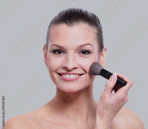 Woman applying dry cosmetic tonal foundation on the face using m