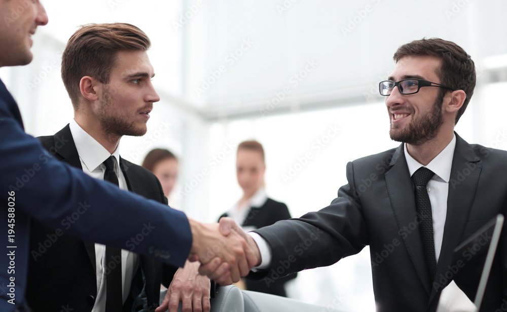 Partners concluding deal and shaking hands in the presence of team members Partners concluding deal and shaking hands in the presence of team members
