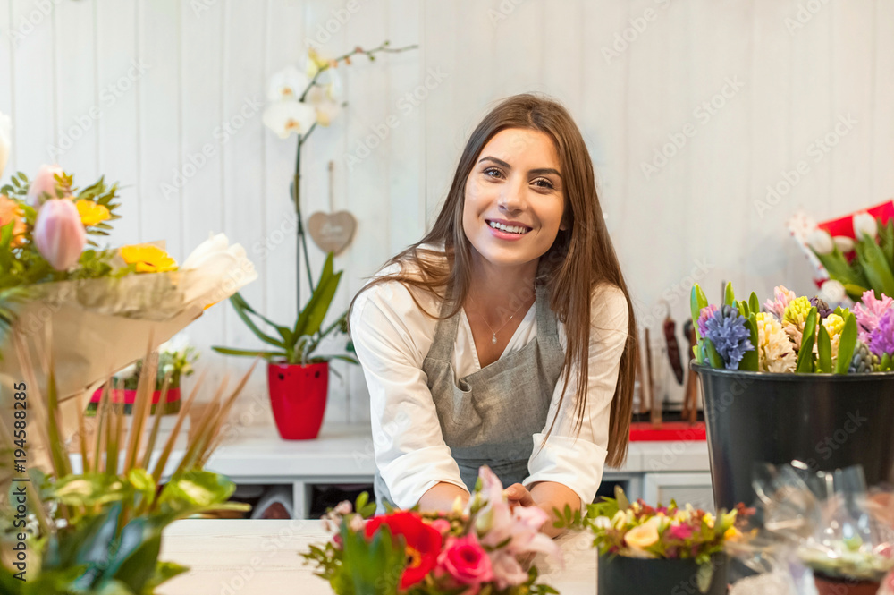 Smiling woman florist small business flower shop owner, at counter, looking friendly at camera. Smiling woman florist small business flower shop owner, at counter, looking friendly at camera.